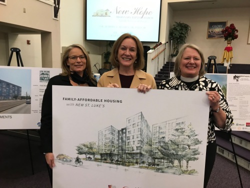 three women standing behind a large poster showing a rendering of a building.