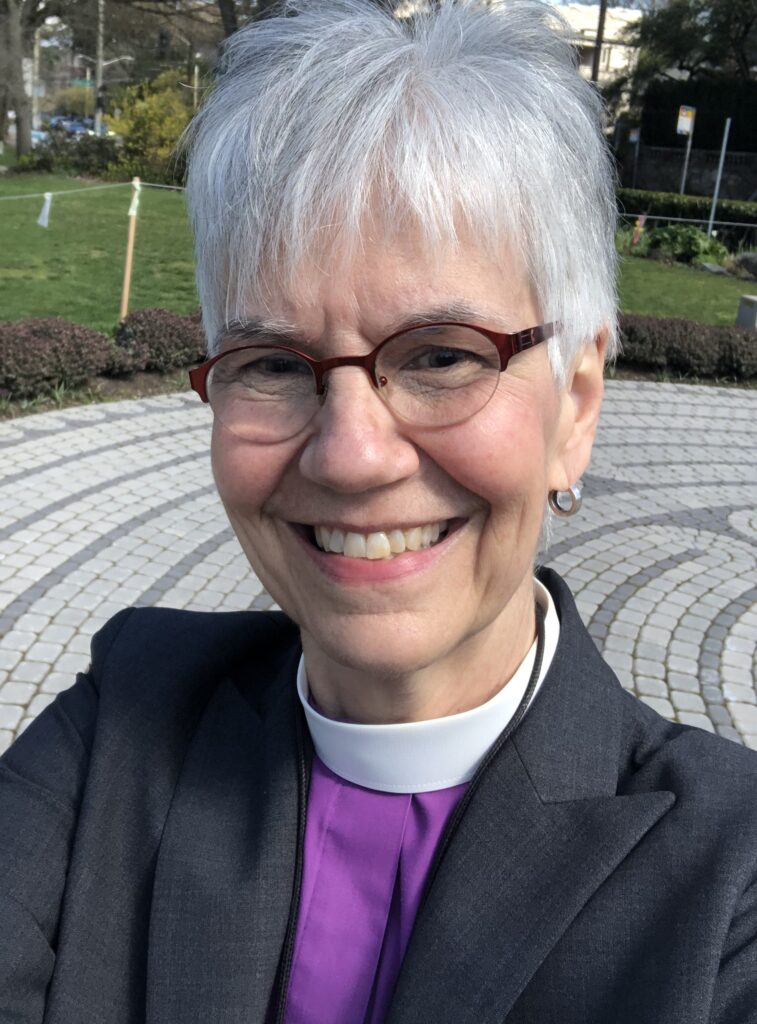 image of older woman smiling with short grey hair and glasses wearing clerical collar