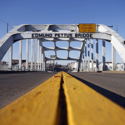 Image of the Edmund Pettus Bridge with road and center yellow stripe in the foreground.