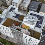 birdseye view of an apartment building rooftop with solar panels, garden space, and play area